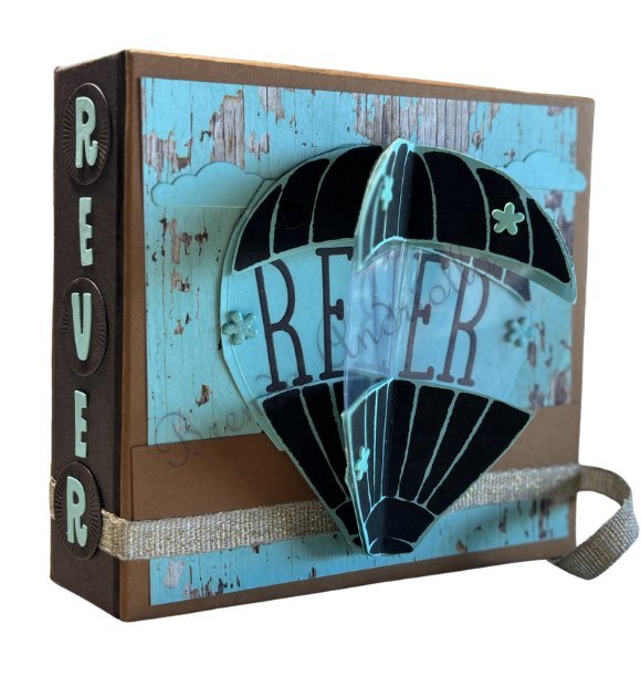 Boîte album bleue « Rêver » ornée d'une montgolfière découpée et de sa sangle en toile