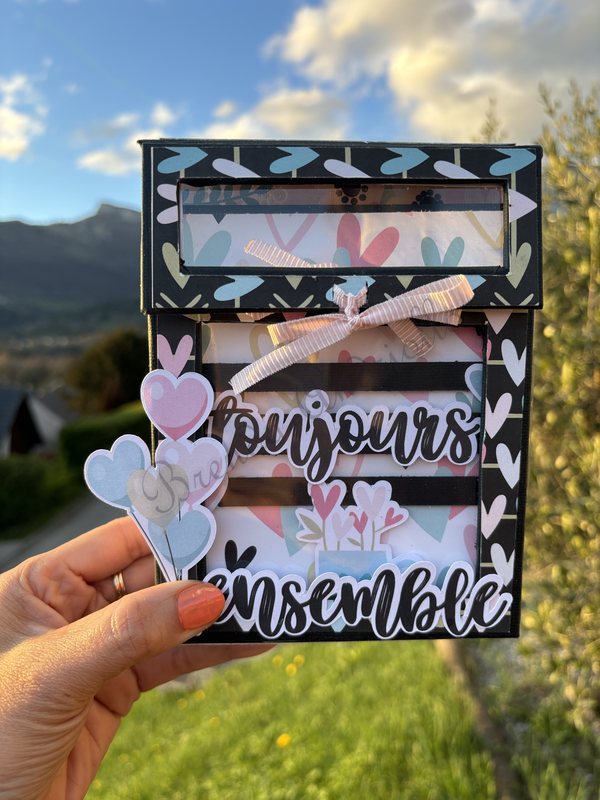 Boîte Toujours ensemble, photographiée face aux montagnes de Savoie